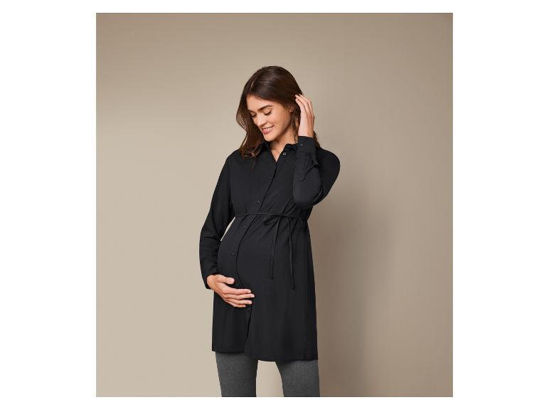 Zwanger vrouw in een zwarte blouse en grijze broek.