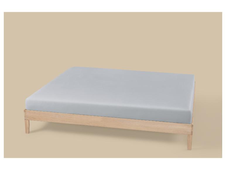 Lichtgrijs matras op een houten bedframe.