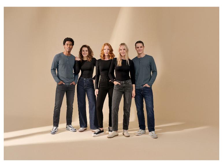Vijf lachende modellen tonen jeans en shirts met lange mouwen op een beige achtergrond.