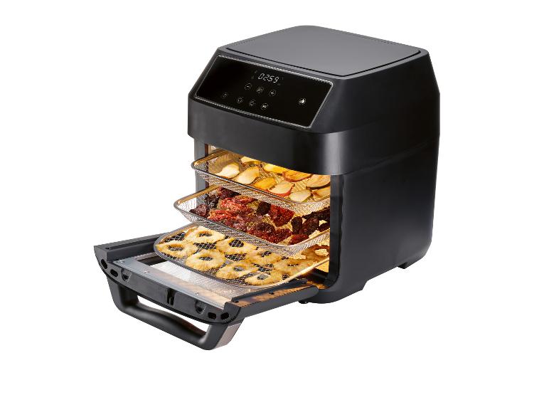 Een zwarte airfryer met daarin gebakken ananas, gedroogde tomaten en appelschijfjes.
