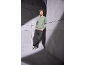 Man in groene sweatshirt met 'Club 1990' tekst, donkere jeans en groene sneakers.