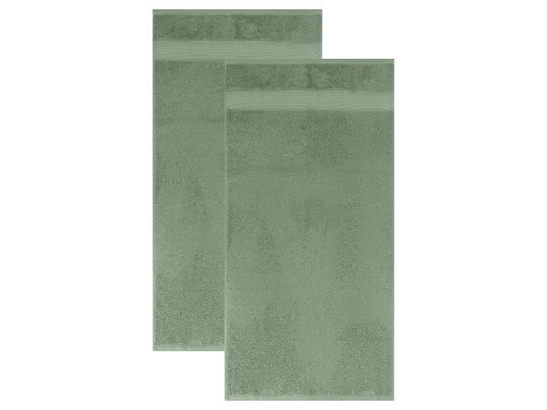 Twee groene badhanddoeken met een getextureerde rand, licht verspringend.