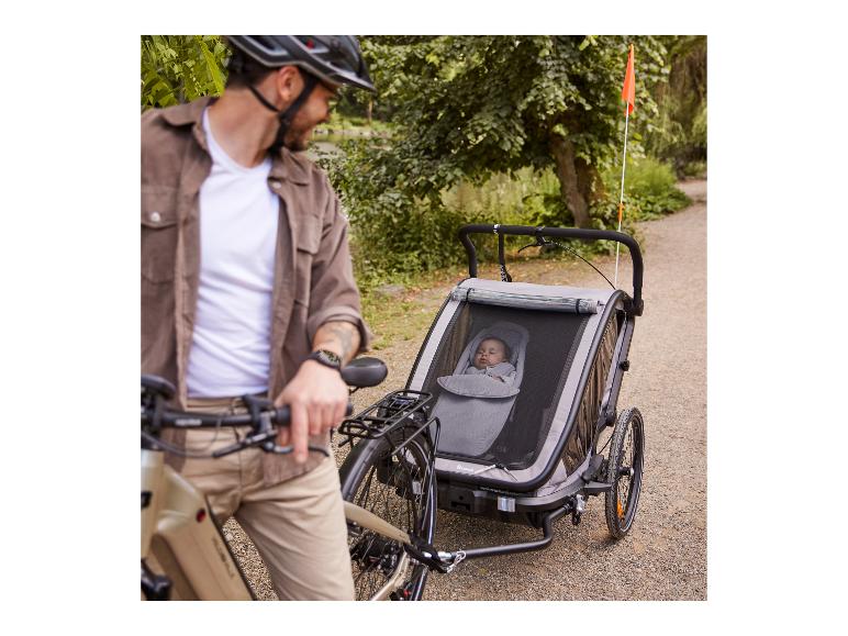 Man met fiets en Hauck fietskar met baby