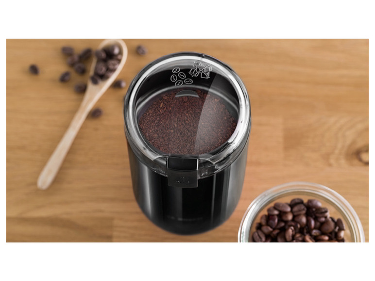 Een zwarte koffiebonenmaler met gemalen koffie en koffiebonen.