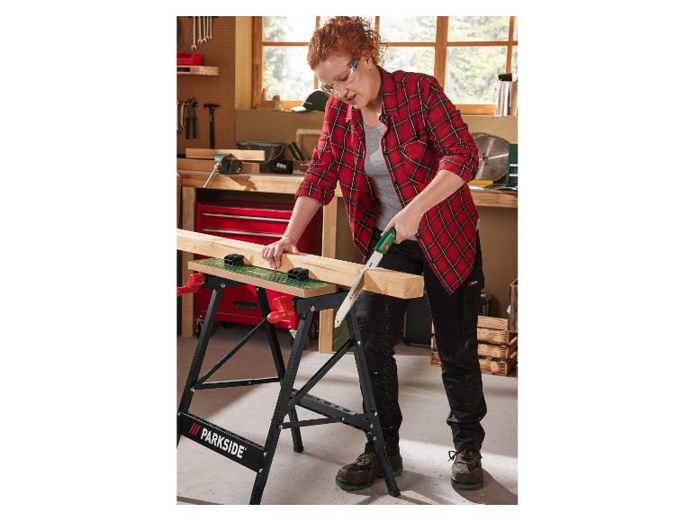 Een vrouw gebruikt een Parkside handzaag om hout te zagen op een werkbank.