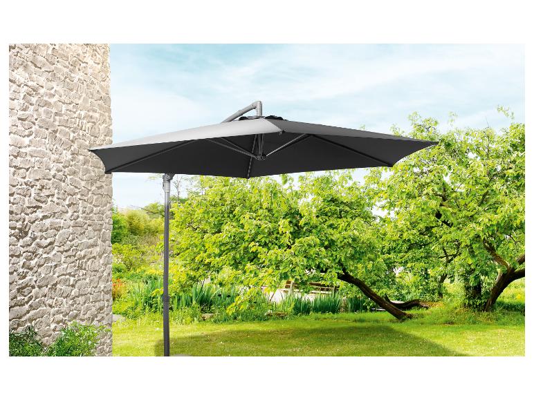 Donkergrijze parasol voor de tuin, aan de muur bevestigd, in een groene tuin.