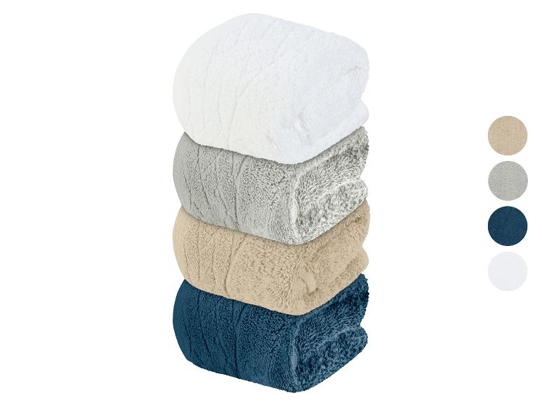 Een stapel badhanddoeken in wit, grijs, beige en blauw.