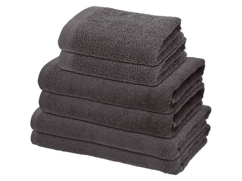 Stapel gevouwen grijze handdoeken van verschillende formaten.