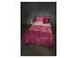 Roze en fuchsia beddengoed met geometrisch patroon op een bed in een donkere slaapkamer.