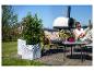 Plantpotten met planten op een houten terras, met een ontspannende vrouw op de achtergrond.