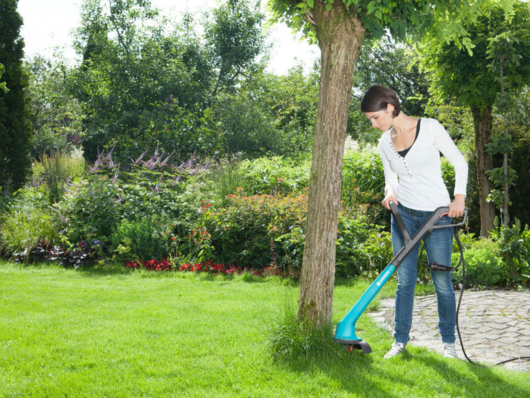 Een vrouw gebruikt een Bosch grasmaaier om onkruid te verwijderen in haar tuin.