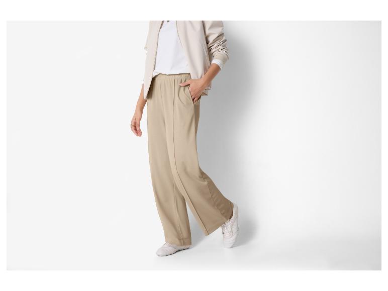 Vrouw in beige broek en wit T-shirt met beige jasje