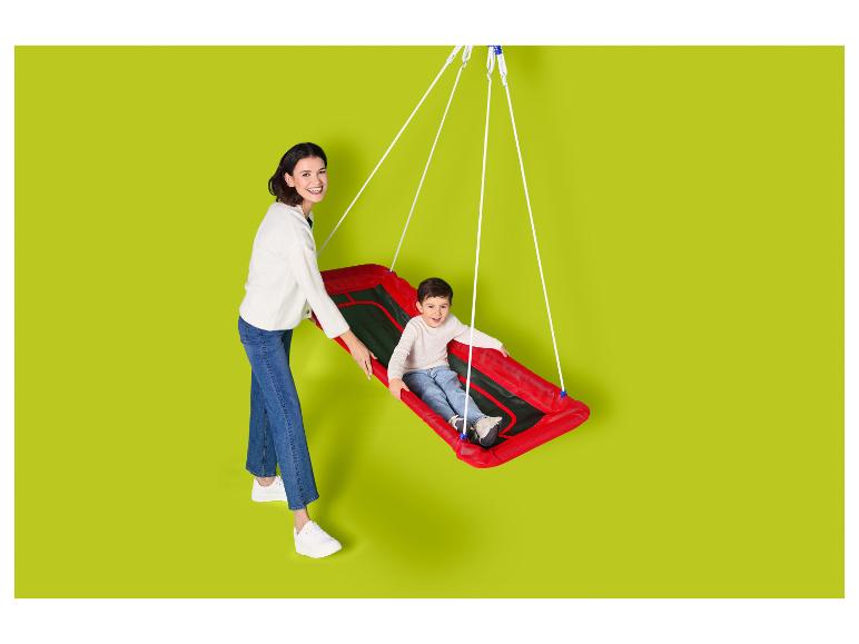 Moeder en kind glimlachen, waarbij het kind in een rode schommel zit.