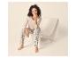 Vrouw in beige shirt met lange mouwen en geruite pyjamabroek zittend op een moderne stoel.