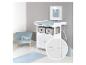 Babykamer met witte commode, blauwe fauteuil en vloerkleed.
