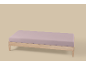 Licht houten bedframe met een lichtpaars matras op een beige achtergrond.