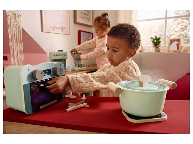 Twee kinderen spelen met speelgoedkeukenapparatuur, waaronder een oven en een pan.