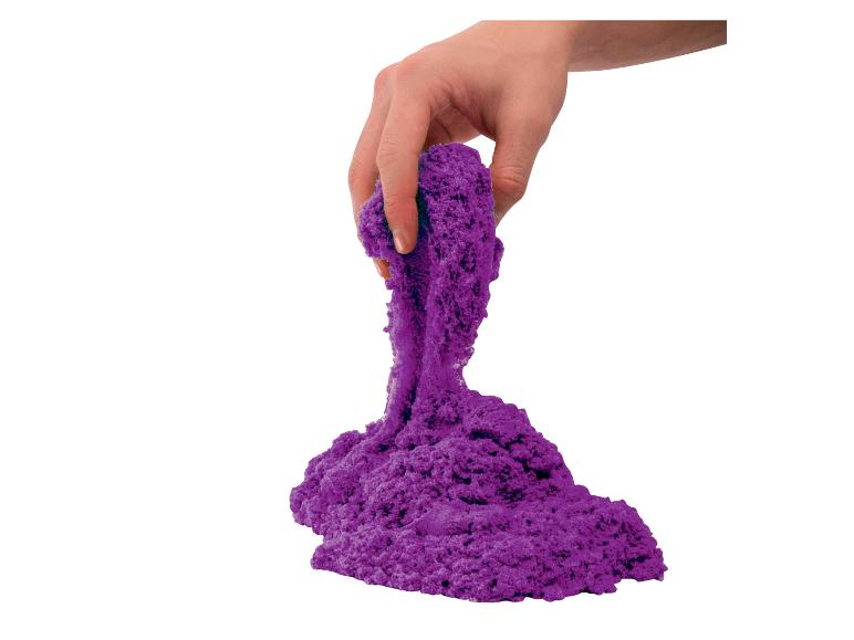 Hand houdt paars kinetisch zand vast dat in een hoop valt.