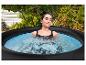 Vrouw ontspant in een buitenjacuzzi, omringd door groen.