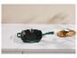 Groene gietijzeren grillpan met houten plank en zout op een wit aanrecht.