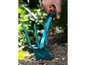 Een blauwe handhark wordt gebruikt om onkruid te wieden in de tuin.