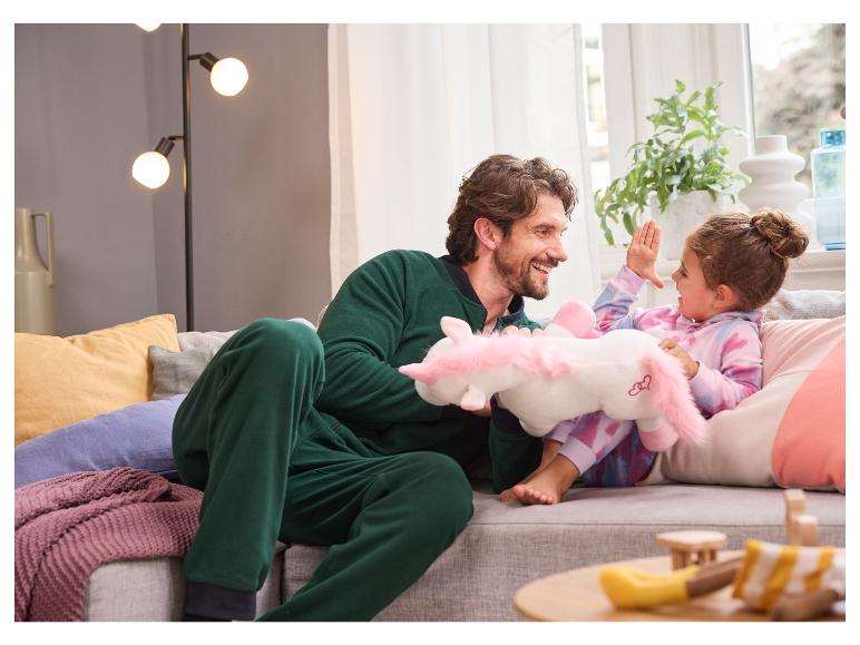 Een vader en dochter spelen met een unicorn knuffel op de bank.
