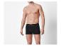 Man zonder shirt in zwarte boxershorts tegen een witte achtergrond.