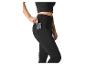 Vrouw in zwarte legging en crop top, stopt een telefoon in de zijzak.