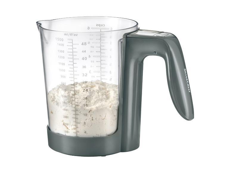 Een grijze Silvercrest digitale keukenweegschaal met een glazen maatbeker, gevuld met bloem.