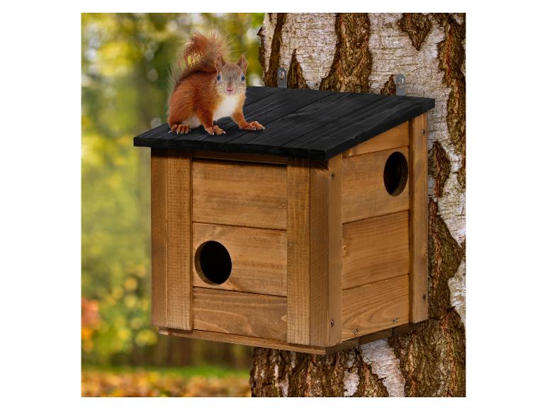 Houten vogelhuisje met een rode eekhoorn op het dak, bevestigd aan een boom.