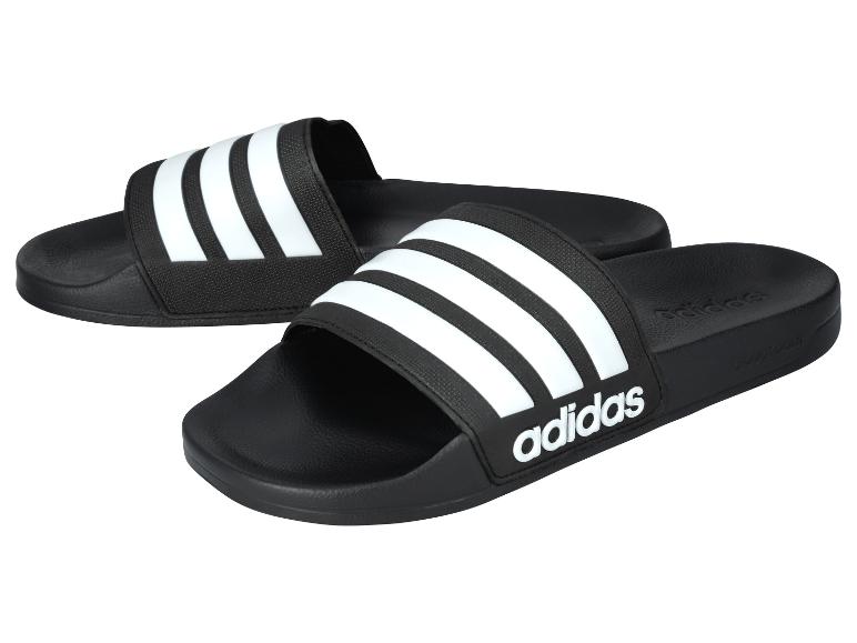Zwarte Adidas slippers met drie witte strepen.