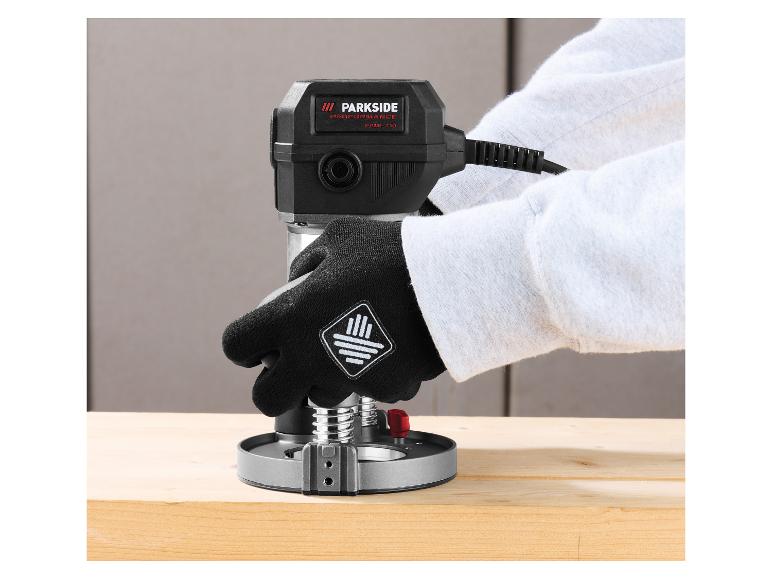 Persoon met handschoenen gebruikt een Parkside Performance bovenfrees op een houten plank