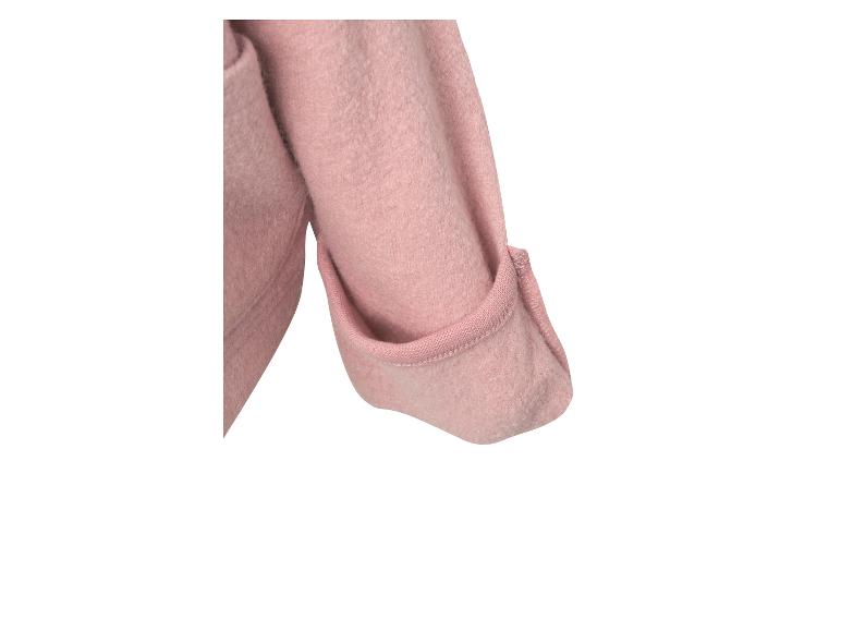 Detail van een roze wollen jas met opgerolde mouw.