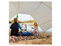 Een gezin geniet van een picknick onder een tent op het strand.
