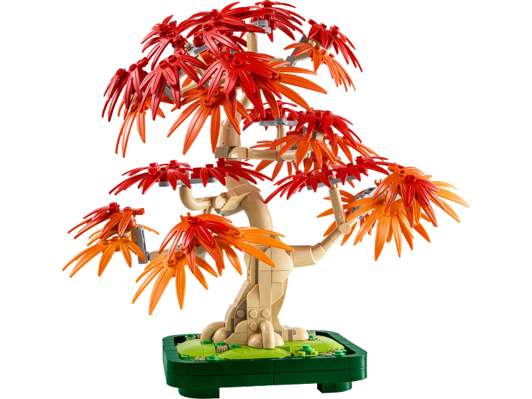 Bonsaiboom van bouwstenen met rode en oranje bladeren op een groene basis.
