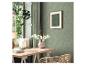 Werkplek met bureau, rotan stoel, groen bloemenbehang en hangplanten.