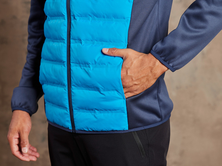 Een man draagt een blauwe, gevoerde jas met een donkerblauwe capuchon