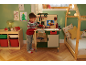 Kind speelt met een speelgoedwerkbank in een kerstthema kamer.