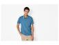 Man in blauw poloshirt en beige broek, poserend met hand in zak.