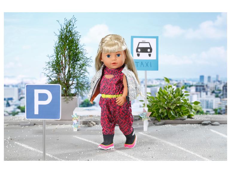 BABY born pop in rode jumpsuit en zilveren vest, met parkeer- en taxiborden.