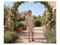 Man in een beige overhemd en korte broek met bladprint, in een tuin.
