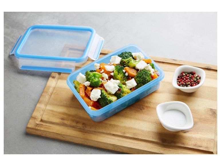 Blauwe voedselcontainer met broccoli- en zoete aardappelsalade met fetakaas, zout en peper.