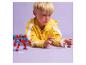 Jongen speelt met een rode robot en een wit figuurtje op een paarse achtergrond.