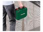 Een persoon draagt een groene PARKSIDE gereedschapskist met rode handvatten in een magazijn.