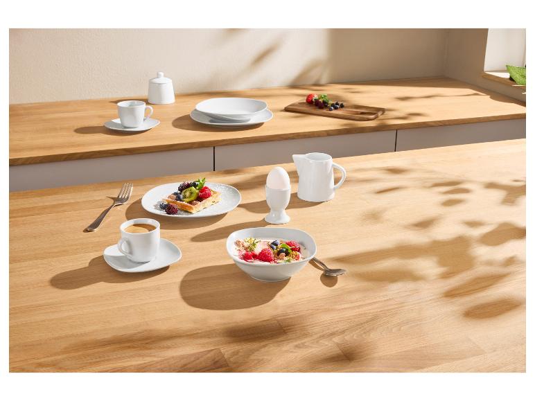 Ontbijt met fruitwafel, yoghurt, koffie en ei op een houten tafel.