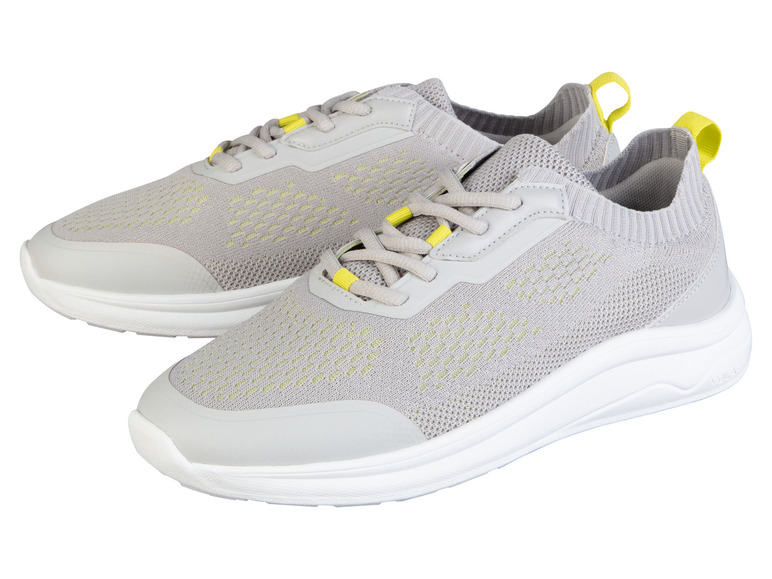 Twee grijze sneakers met gele details.