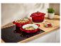 Drie rode Le Creuset pannen op een inductiekookplaat.