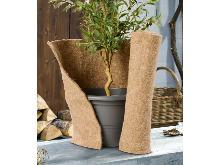 Plant in pot gewikkeld in jute beschermmat, met hout en mand op de achtergrond.