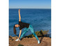 Een vrouw in sportkleding doet yoga oefeningen aan de kust.