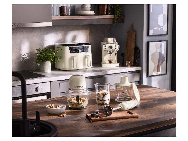 Keuken met crèmekleurige airfryer, espressomachine en blender op een houten aanrecht.